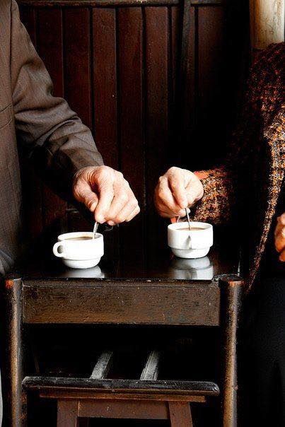 Dos personas mayores compartiendo un café mientras revuelven sus tazas en un encuentro del Club Social Mente Viva