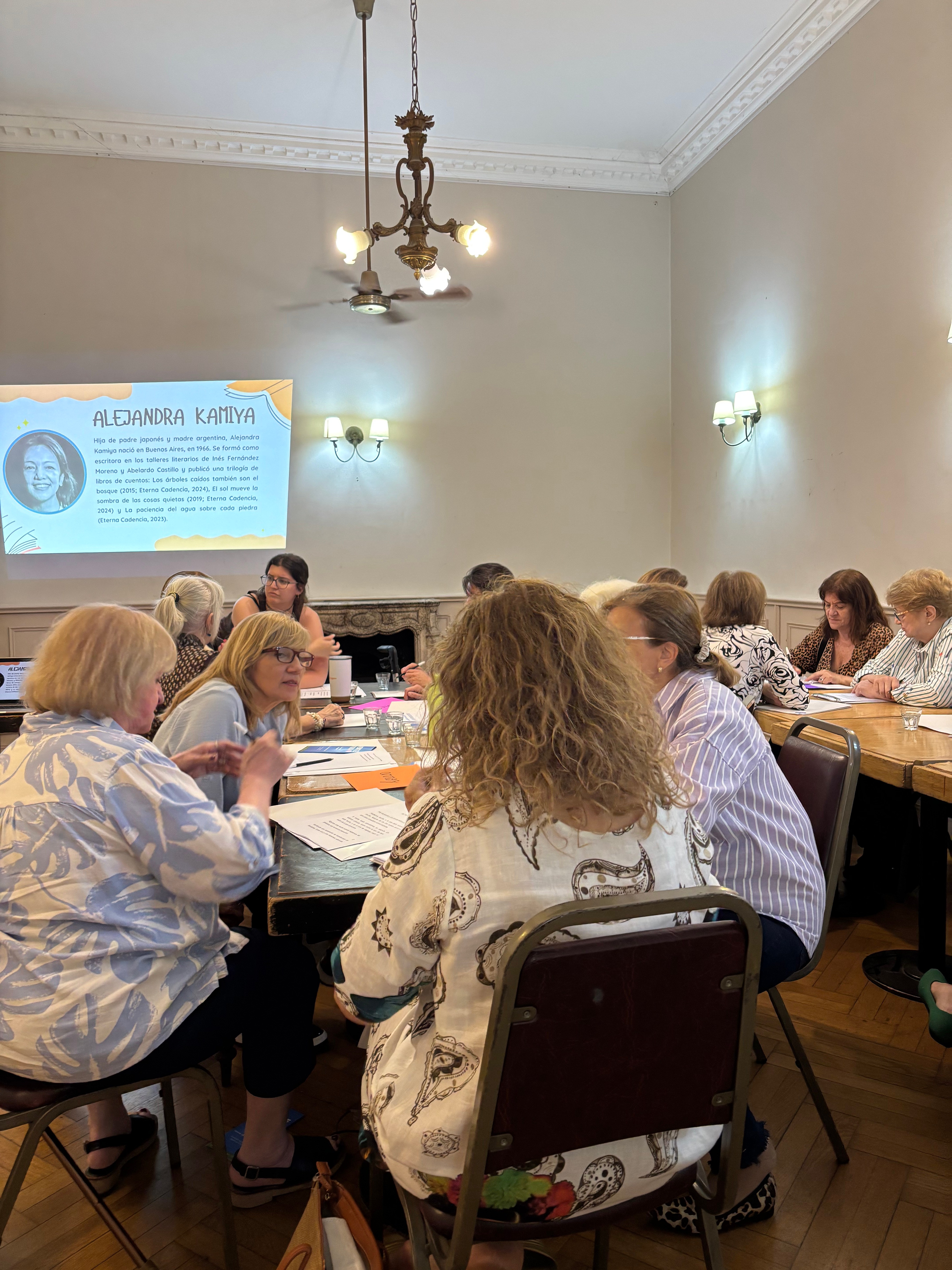 Participantes sentadas alrededor de la mesa conversando y trabajando con textos literarios durante el encuentro de neurolectura en el salón de Recoleta.